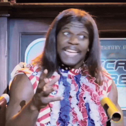 A Man With Long Hair And A Red White And Blue Shirt Is Holding A Microphone GIF