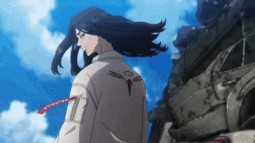 A Man With Long Hair And A Tattoo On His Back Is Standing In Front Of A Pile Of Junk . GIF