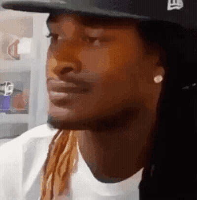 A Man With Long Hair And Dreadlocks Wearing A Hat And Earrings . GIF