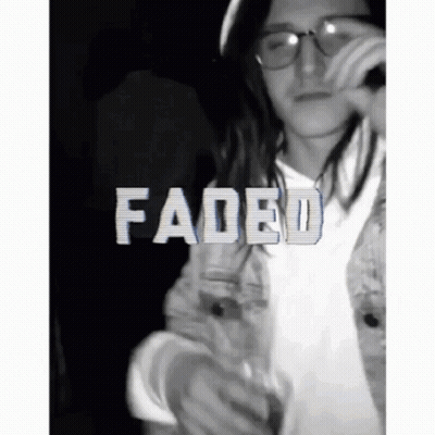 A Man With Long Hair And Glasses Is Holding A Microphone And The Word Faded Is On The Bottom GIF