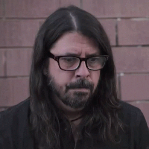 A Man With Long Hair And Glasses Looks Serious GIF