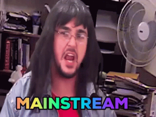 A Man With Long Hair And Glasses Says Mainstream In A Room GIF