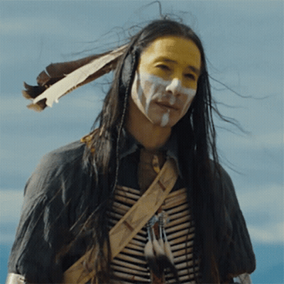 A Man With Long Hair And White Paint On His Face Is Wearing A Native American Outfit GIF