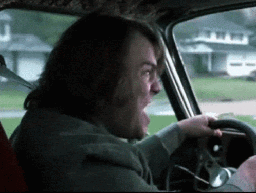 A Man With Long Hair Is Driving A Car And Shouting GIF