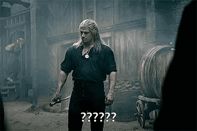 A Man With Long Hair Is Holding A Sword In His Hand In Front Of Barrels . GIF