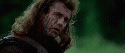 A Man With Long Hair Is Laying In The Grass With Blood On His Face . GIF