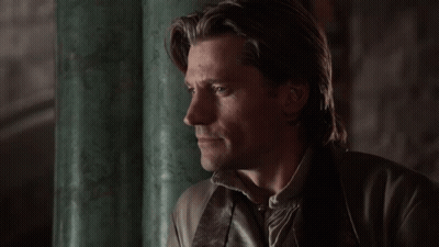 A Man With Long Hair Is Leaning Against A Green Pillar GIF