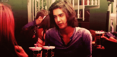 A Man With Long Hair Is Looking At A Woman While Sitting At A Table With Drinks In Front Of Him .. GIF