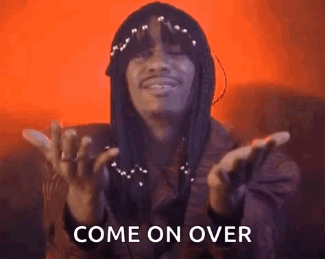 A Man With Long Hair Is Making A Come On Over Sign With His Hands . GIF