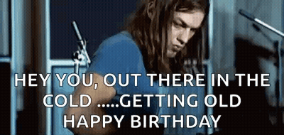 A Man With Long Hair Is Playing A Guitar In Front Of A Microphone In A Room . GIF