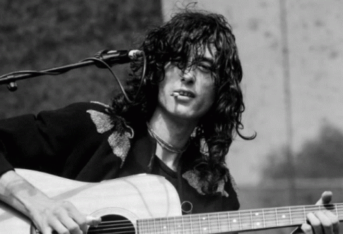 A Man With Long Hair Is Playing An Acoustic Guitar And Smoking A Cigarette GIF