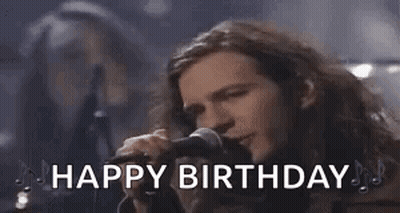 A Man With Long Hair Is Singing Into A Microphone With The Words `` Happy Birthday '' . GIF