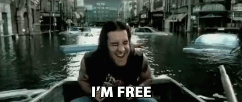 A Man With Long Hair Is Sitting In A Boat In A Flooded City . GIF