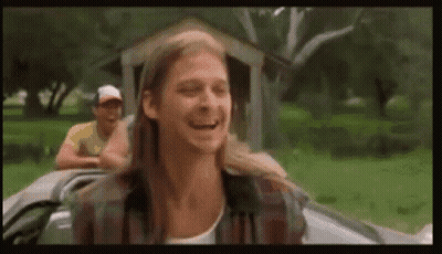 A Man With Long Hair Is Sitting In A Car Laughing . GIF