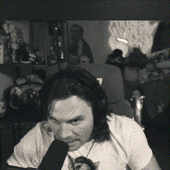 A Man With Long Hair Is Sitting In Front Of A Microphone With A Cat On His Lap GIF
