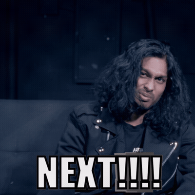 A Man With Long Hair Is Sitting Next To A Sign That Says Next GIF