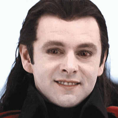 A Man With Long Hair Is Smiling And Wearing A Black Turtleneck GIF