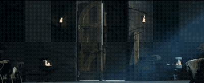 A Man With Long Hair Is Standing In A Dark Room Holding A Door Open GIF