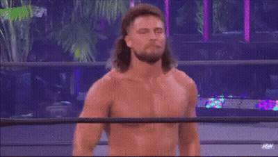 A Man With Long Hair Is Standing In A Wrestling Ring Without A Shirt On . GIF