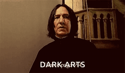 A Man With Long Hair Is Standing In Front Of A Building With The Words `` Dark Arts '' Written On His Face . GIF