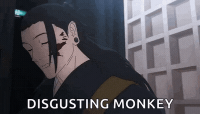 A Man With Long Hair Is Standing In Front Of A Building With The Words Disgusting Monkey Written On It . GIF