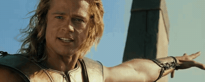 A Man With Long Hair Is Standing In Front Of A Tower With His Arm Outstretched . GIF