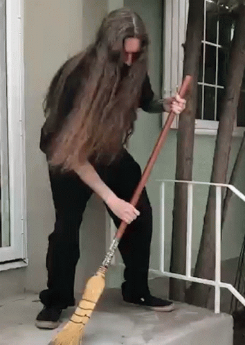 A Man With Long Hair Is Sweeping The Floor With A Broom GIF