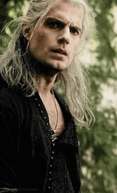 A Man With Long Hair Is Wearing A Black Shirt And A Necklace . GIF