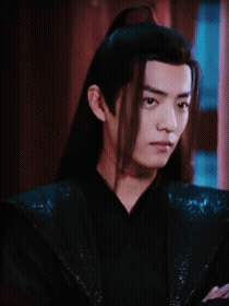 A Man With Long Hair Is Wearing A Black Shirt And Has A Red Spot On His Neck GIF