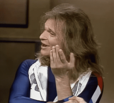 A Man With Long Hair Is Wearing A Blue White And Red Shirt GIF