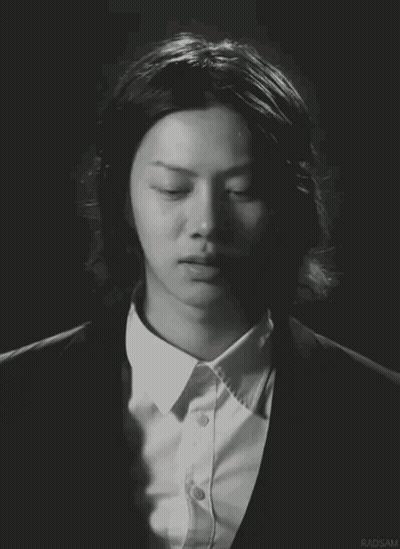 A Man With Long Hair Is Wearing A Suit And A White Shirt With Radsam Written On The Bottom GIF