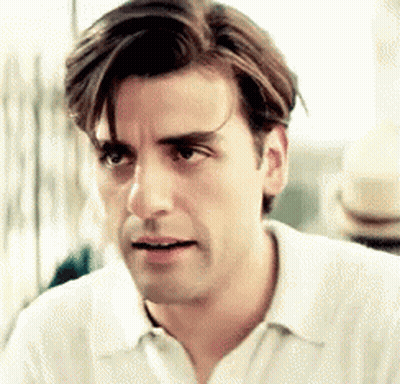 A Man With Long Hair Is Wearing A White Shirt And Looking At The Camera . GIF