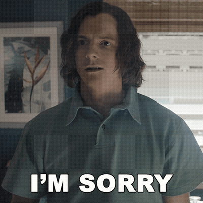 A Man With Long Hair Says I 'M Sorry In Front Of A Window GIF