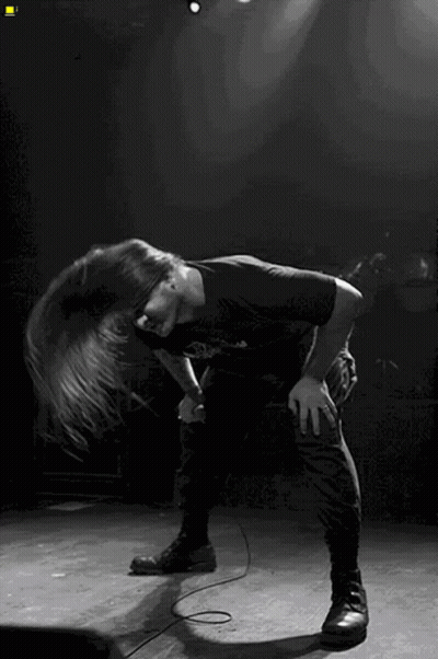 A Man With Long Hair Singing Into A Microphone On Stage GIF