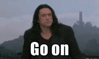 A Man With Long Hair Stands In Front Of A Sign That Says " Go On " GIF