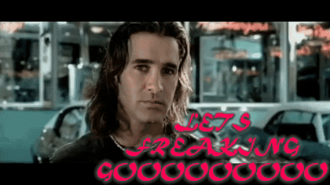 A Man With Long Hair Stands In Front Of A Sign That Says " Let 'S Freaking Gooooo " GIF