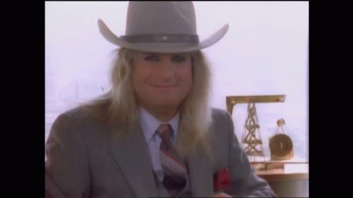 A Man With Long Hair Wearing A Cowboy Hat And Suit GIF