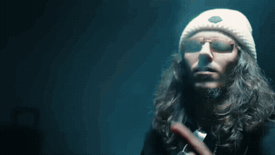 A Man With Long Hair Wearing Sunglasses And A White Hat Points To The Word My GIF