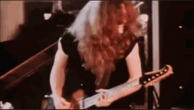 A Man With Long Red Hair Is Playing A Guitar In A Room . GIF