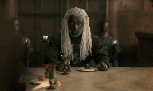 A Man With Long White Dreadlocks Sits At A Table GIF