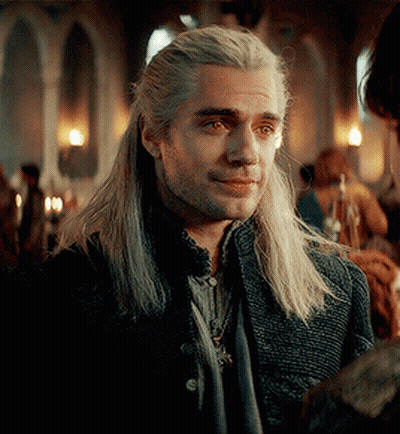 A Man With Long White Hair And A Beard Is Wearing A Black Jacket And Scarf . GIF