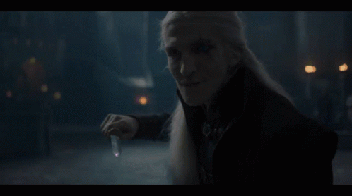 A Man With Long White Hair Is Holding A Candle In His Hand GIF