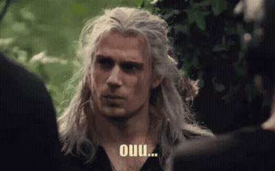 A Man With Long White Hair Is Standing In Front Of A Group Of People And Talking To Them . GIF