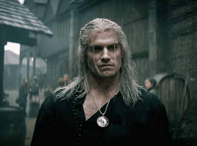A Man With Long White Hair Is Wearing A Necklace With A Dragon Pendant GIF