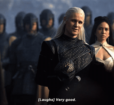 A Man With Long White Hair Says [ Laughs ] Very Good In Front Of A Group Of People GIF