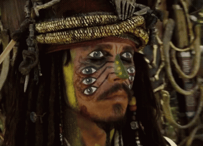 A Man With Many Eyes Painted On His Face Looks At The Camera GIF
