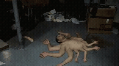 A Man With Many Hands Is Laying On The Floor In A Basement . GIF