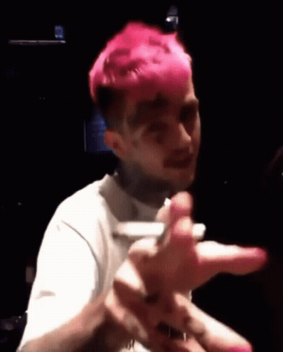 A Man With Pink Hair Is Making A Funny Face While Holding A Cell Phone In A Dark Room . GIF