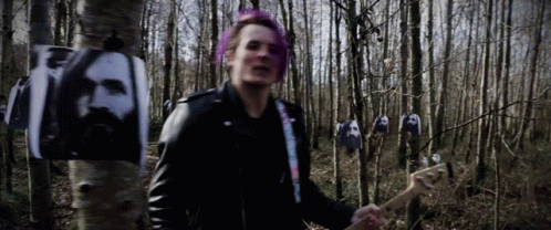 A Man With Pink Hair Is Playing A Guitar In A Forest GIF