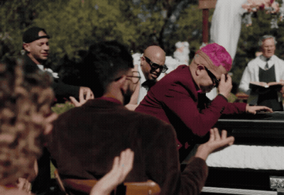 A Man With Pink Hair Is Sitting In A Coffin GIF
